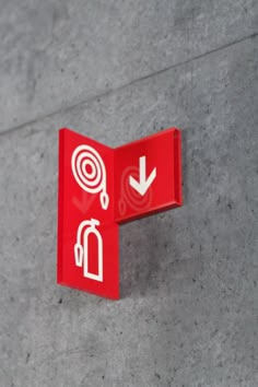 a red fire extinguisher sign mounted on the side of a cement wall