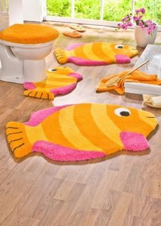 a bathroom with yellow and pink fish rugs on the floor next to a toilet