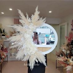 there is a woman taking a photo in the mirror with her cell phone and some feathers on display