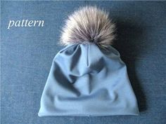 a blue beanie with a silver pom - pom on top