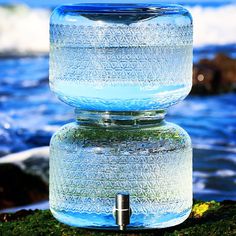 there is a large water bottle on top of the rocks by the water's edge