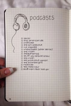 a hand holding an open notebook with headphones on it and the words podcasts written in cursive writing