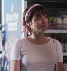 a woman standing in front of a vending machine smiling at the camera while wearing a pink headband