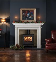 a living room with a fire place next to a red chair and christmas decorations on the mantle