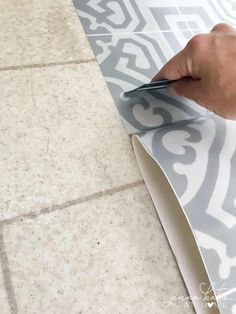 a person is using scissors to cut out the pattern on a tile floor that's being installed