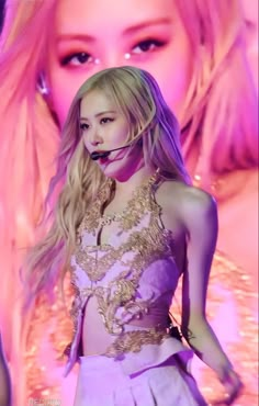 a woman with long blonde hair wearing a purple dress in front of a pink background