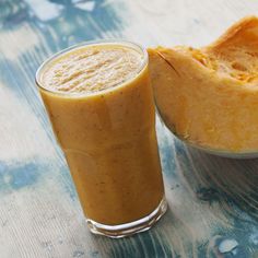 a smoothie in a glass next to a half - eaten banana on a table