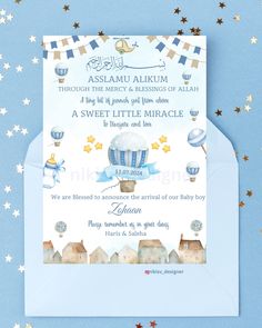 a blue and white baby shower card with stars on the bottom, and an air balloon in the middle