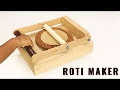 a person is holding a rolling board in a wooden box with the words roti maker on it