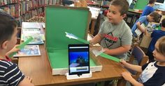 two children are playing with an ipad in a library