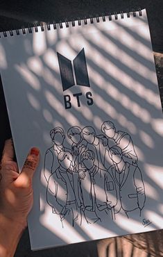 a person holding up a paper with the bts logo on it