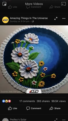 a cake decorated with white flowers and green leaves on top of a blue plate that reads amazing things in the universe