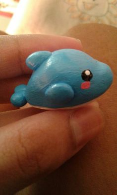 a small blue toy whale sitting on top of someone's finger