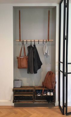 a coat rack with several coats hanging on it and two purses next to it