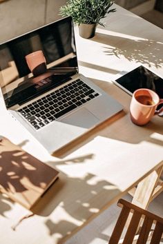 an open laptop computer sitting on top of a wooden table next to a cup of coffee