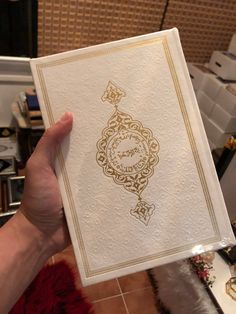 a person holding up a card with an ornate design on the front and back cover