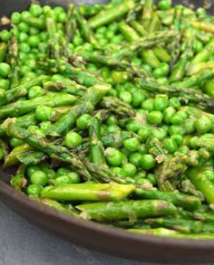 peas and asparagus in a brown bowl on a gray table top, ready to be cooked