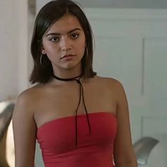 a woman in a strapless red dress is looking at the camera with an intense look on her face