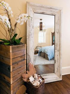 a mirror sitting on top of a wooden floor next to a basket filled with flowers