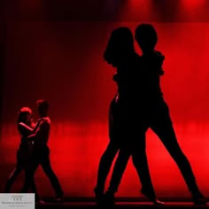 silhouettes of people dancing on stage with red lighting