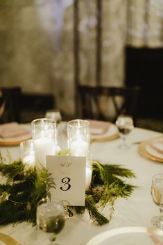 the table is set with candles and greenery