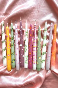 seven candles are lined up on a pink sheet