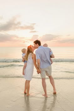 a family kissing on the beach at sunset