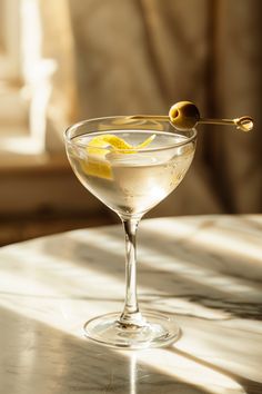 a martini glass with an olive on the rim and lemon wedges sticking out of it