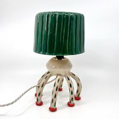 an octopus lamp with a green shade on it's base and red feet is shown against a white background