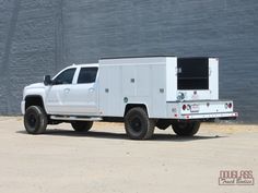 a white truck is parked in front of a brick wall with the back door open