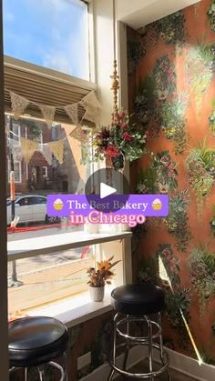 the inside of a restaurant with floral wallpaper and bar stools in front of a window