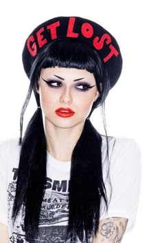 a woman with long black hair wearing a hat that says get lost on the side