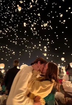 a man and woman kissing in front of floating lanterns