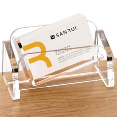 a clear acrylic business card holder on a wooden table with a logo for sanfui