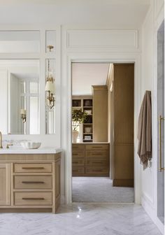 a bathroom with marble counter tops and wooden cabinets, along with an open door leading to another room