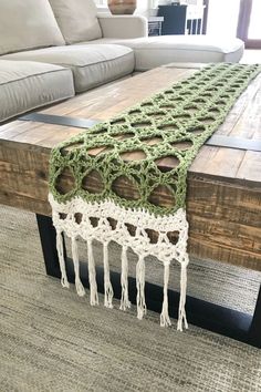 the table is made out of wood and has a green crochet runner on it