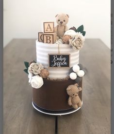 a baby shower cake with teddy bears and flowers on the top, sitting on a wooden table