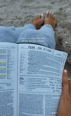 a person laying on the ground reading a book with their feet propped up in front of them