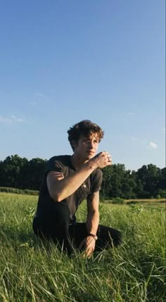 a young man sitting in the middle of a field