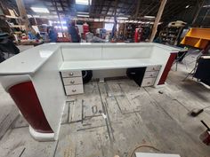 a white desk with red and black drawers in a room filled with other furniture items