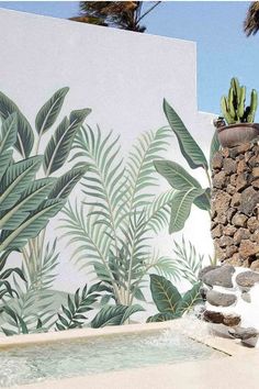 a wall with plants painted on it next to a pool