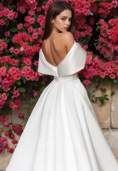 a woman standing in front of flowers wearing a white dress