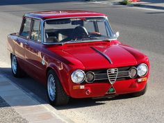 an old red car is parked on the side of the road in front of a curb