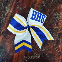 a blue and yellow cheer bow sitting on top of a wooden table