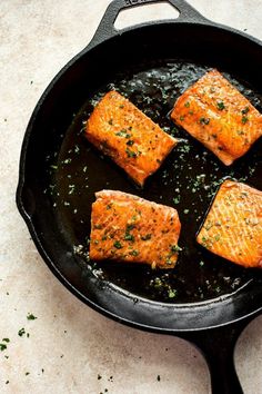 four cooked salmon fillets in a skillet