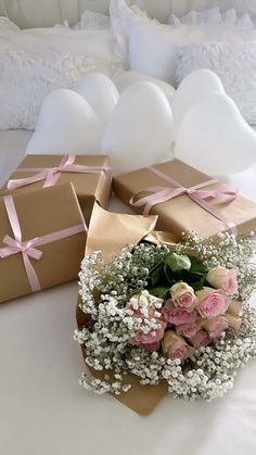 two boxes with pink and white flowers in them on a bed next to each other