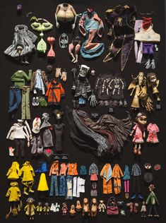 an assortment of doll clothes and accessories displayed on a black surface