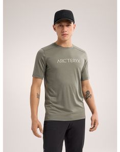 a man wearing a grey arcteryx shirt and black cap with white writing on it