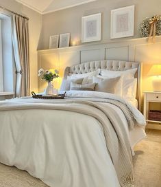 a bed with white sheets and pillows in a bedroom next to two lamps on either side of the bed