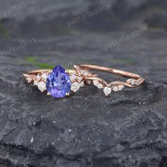 an engagement ring with a tan and blue stone surrounded by white diamonds on top of a rock